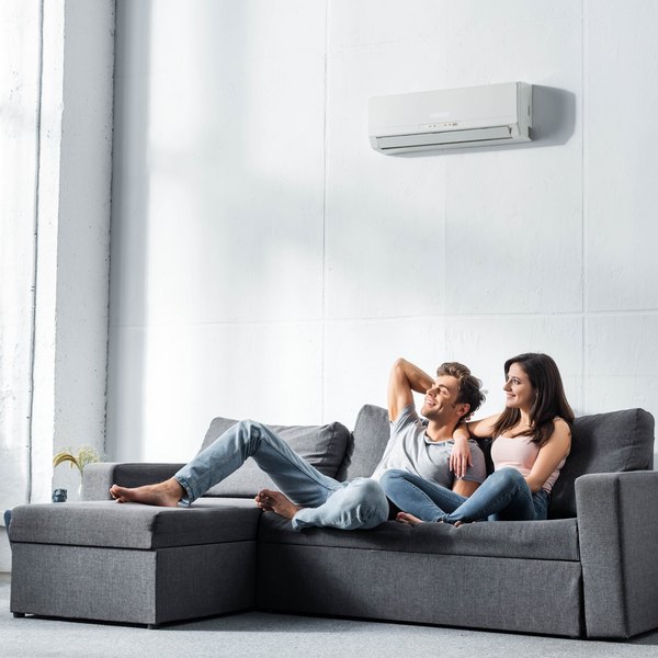 Paar entspannt auf Sofa unter einer Wand-Klimaanlage